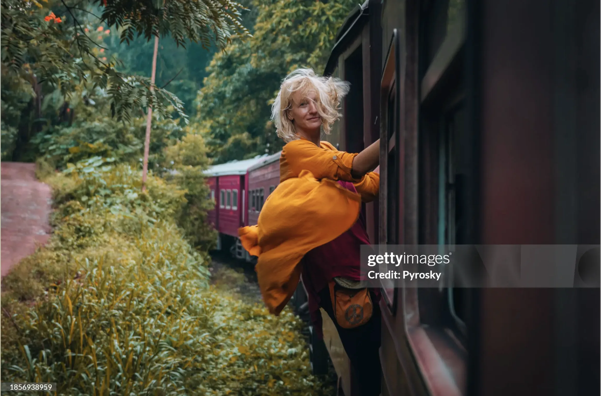 Blonde Traveler Leaning Out of Vintage Train Through Jungle