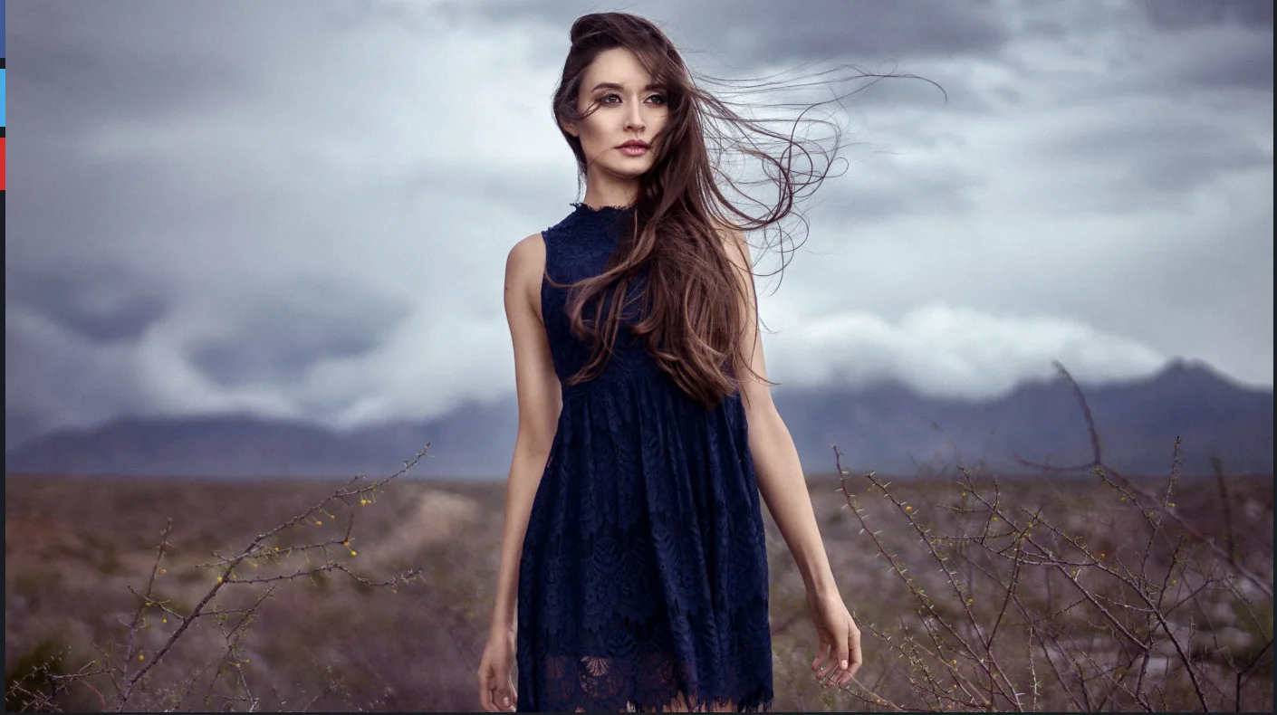 Windswept Woman in Navy Lace Dress Against Desert Storm Sky